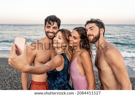 Young people having fun taking selfies on the beach - millennials in swimsuit taking pictures on summer