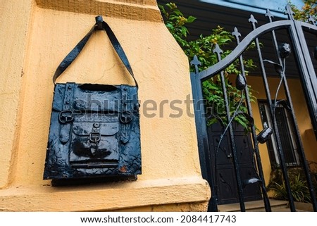 Bag-shaped iron mailbox hanging on a wall fence.