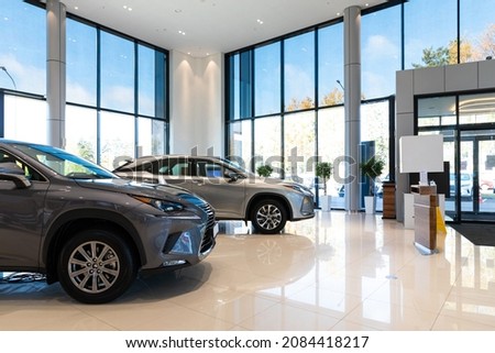 two gray premium SUVs in a dealership showroom with huge windows and modern interior Royalty-Free Stock Photo #2084418217