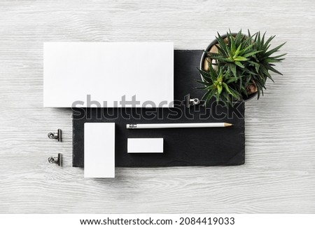 Corporate identity template. Blank envelope, business card, pencil, eraser, clips and succulent plant on stone board. Flat lay.