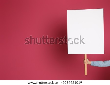 Woman holding blank sign on pink background, closeup. Space for design