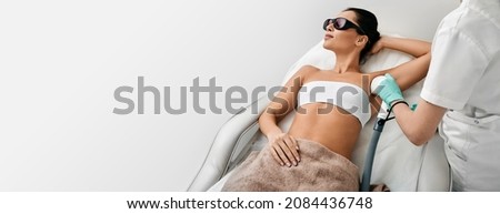 Woman during underarm laser hair removal and armpit laser epilation at beauty center. Laser epilation concept, web banner with space for text Royalty-Free Stock Photo #2084436748
