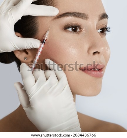 Beautiful woman receives anti wrinkle beauty injection for facial rejuvenation and wrinkle removal. Facial mesotherapy, eye wrinkle injection Royalty-Free Stock Photo #2084436766