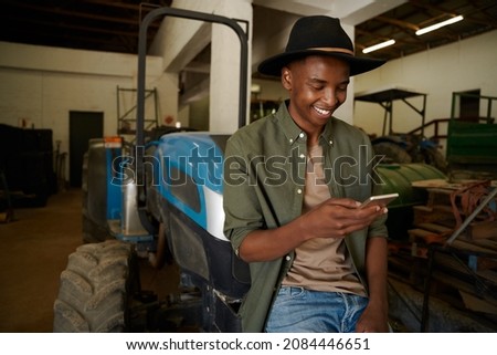 Mixed race female farmer standing in shed texting on cellular device Royalty-Free Stock Photo #2084446651