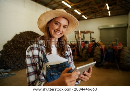 caucasian female farmer smiling while holding digital tablet