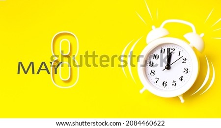 May 8th. Day 8 of month, Calendar date. White alarm clock with calendar day on yellow background. Minimalistic concept of time, deadline. Spring month, day of the year concept