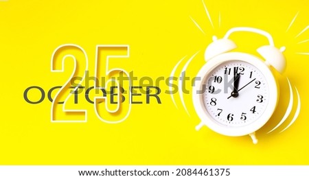 October 25th. Day 25 of month, Calendar date. White alarm clock with calendar day on yellow background. Minimalistic concept of time, deadline. Autumn month, day of the year concept
