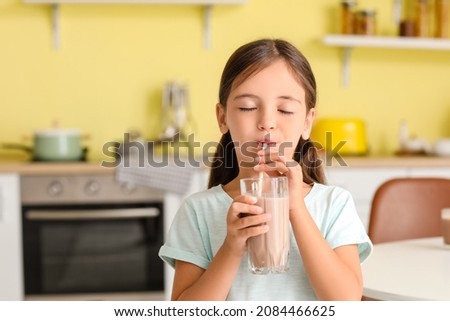 Little girl drinking tasty chocolate milk at home Royalty-Free Stock Photo #2084466625
