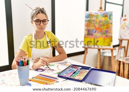 Young brunette teenager at art studio depressed and worry for distress, crying angry and afraid. sad expression. 