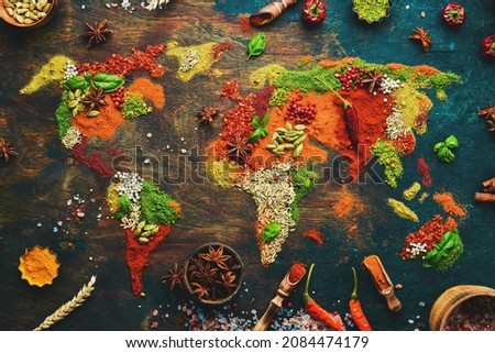 Spices and herbs around the world in the shape of a world map on a dark background. Top view. Creative photo banner. Royalty-Free Stock Photo #2084474179