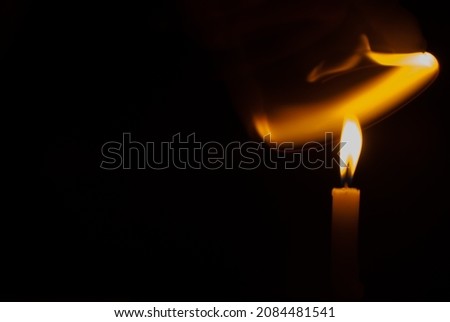 Blurred candlelight, front view with light of candle flame blowing in the wind on black background. Ideas for Halloween, Christmas, Home, Romance, Love, Copy space for you.