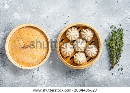 Steamed baozi dumplings stuffed with meat in a bamboo steamer. Gray background. Top view Royalty-Free Stock Photo #2084486629