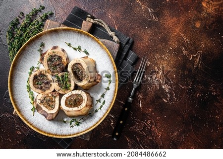 Baked marrow veal beef bones in plate with thyme and herbs. Dark background. Top view. Copy space Royalty-Free Stock Photo #2084486662