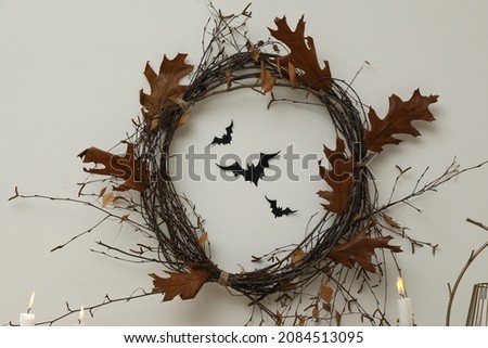 Wreath made with dry branches and leaves on white wall. Halloween decor