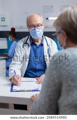 Specialist taking notes on clipboard papers while doing consultation with woman during covid 19 pandemic. Man doctor preparing prescription document for treatment against disease.