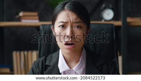 Shocked asian business woman looks at the camera with fear of terrible news, while sitting at office. Portrait of scared female student, reaction on bad news, sitting indoors at home office. 4K Royalty-Free Stock Photo #2084522173