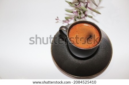Close-up shot of a cup of Turkish coffee and green othonna capensis succulent plant in a black cup
