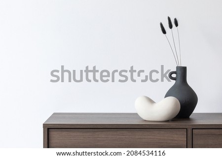 Creative living room composition with white wall and stylish minimalisitc small home accessories on wooden commode. Copy space. Template. Royalty-Free Stock Photo #2084534116