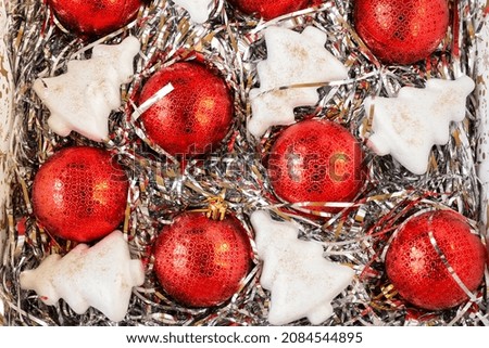Red Christmas balls and white artificial Christmas trees on decorations in a box, top view, background