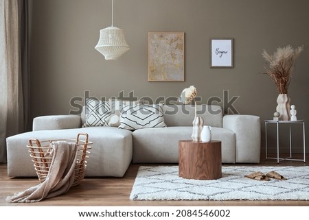 Interior design of stylish living room with modern neutral sofa, mock up poster farmes, dried flowers in vase, coffee tables, decoration and elegant personal accessories in home decor. Template.