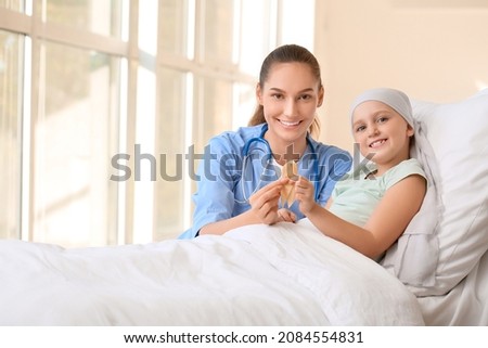 Nurse and little girl with golden ribbon in clinic. Childhood cancer awareness concept Royalty-Free Stock Photo #2084554831