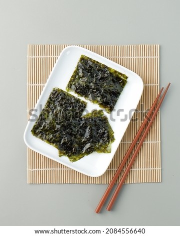 Isolated japanese seaweed nori served in rectangle plate with wooden chopstick. Seaweed nori to make sushi and onigiri japanese food. Seaweed nori from top angle flat lay photography.