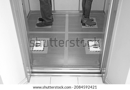 Monochrome image of people facing the wall in the elevator for social distancing to stay safe from the infection