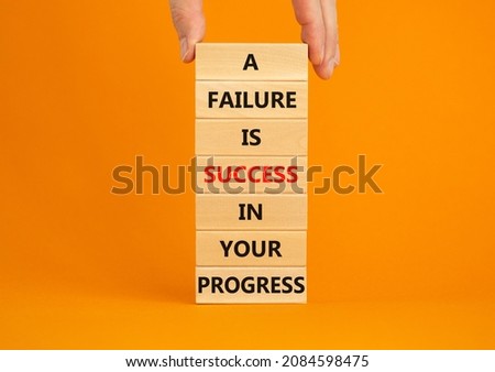 Failure or success symbol. Wooden blocks with words A failure is success in your progress. Beautiful orange background, copy space. Businessman hand. Business, failure or success concept.