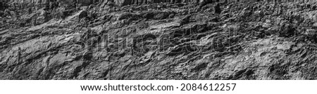 Grungy cragged bumpy pitted cavity stone facade, split layer gap.Ruined cracked shattered worn rough hiking canyon.Old ragged grunge steep marble cliff. Grand vintage crannied damaged impressive gorge Royalty-Free Stock Photo #2084612257