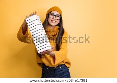 Portrait of smiling cheerful young girl with big present box isolated over yellow background. Happy holidays. Concept of beauty, youth, facial expression, emotions, lifestyle. Copy space for ad
