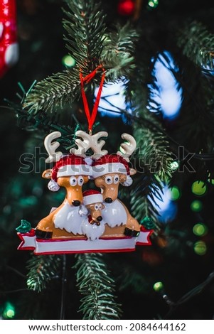 Christmas toy figurines of funny deers in a Santa Claus hat hanging on the Christmas tree branches. New Year festive details