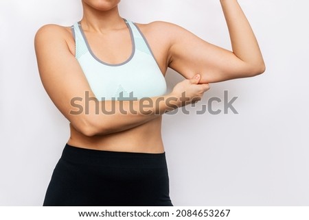 Cropped shot of young caucasian woman grabbing skin on her upper arm with excess fat isolated on a white background. Overweight, excess weight. Pinching the loose and saggy muscles.Taking care of body Royalty-Free Stock Photo #2084653267