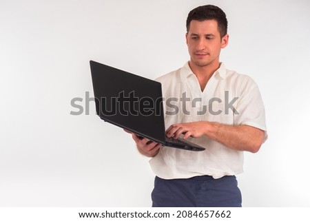 Man in shirt holds a laptop. Portrait of guy on white background. Focused office worker. Man in an office uniform with computer. It works or configures something. Concept - sale of laptop.