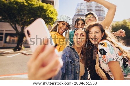 Vibrant young people taking a selfie together. Cheerful generation z friends having fun while hanging out together in the city. Multiethnic group of friends capturing their happy moments in the sun.