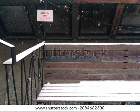 The place to sit is a bench covered with snow. The inscription in Russian "do not smoke"