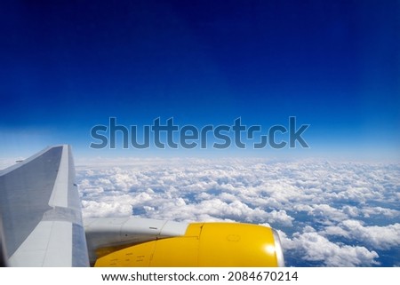 Aerial photography. View from the plane window: aircraft turbine, blue skies, fluffy cirrus clouds. Flying above the clouds. Horizontal photo. Travel and tourism, air transport and nature concept. 