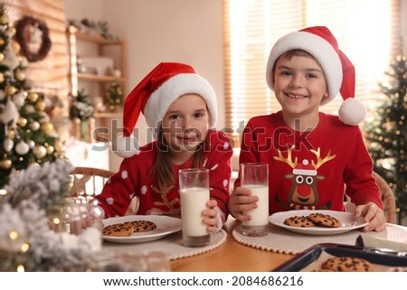 Cute little children with delicious Christmas cookies and milk at home