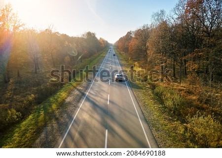 Aerial view of intercity road with fast driving cars between autumn forest trees at sunset. Top view from drone of highway traffic in evening Royalty-Free Stock Photo #2084690188