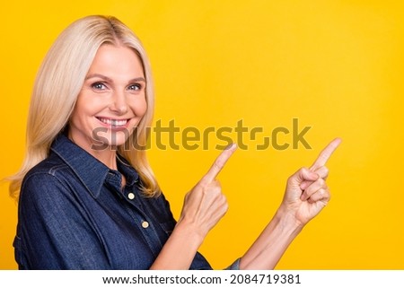 Photo of cute shiny lady pensioner dressed denim outfit pointing empty space isolated yellow color background