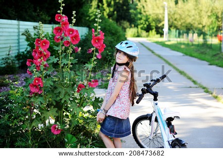 Adorable kid girl in blue helmet going to ride her bike 