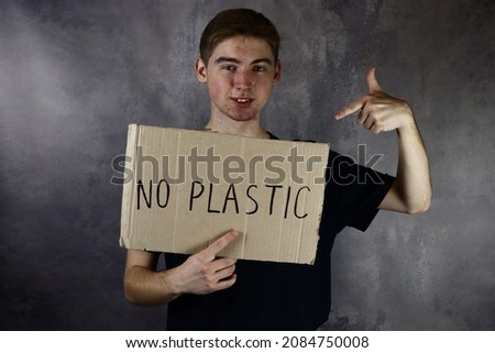 young man holds a poster, a cardboard with the text no plastic
