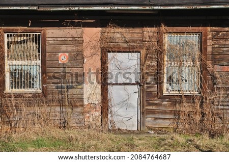 facade of an abandoned wooden old house with dilapidated door and rusty windows with bars no smoke