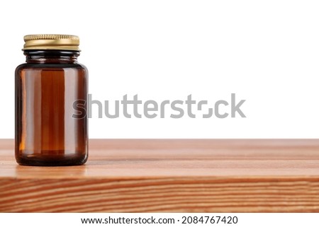 Wooden table on white background with brown medical bottle. Concept of herbal medicine, pill dish, tablet container.