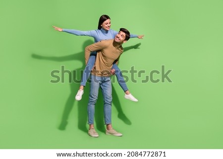 Photo of two carefree people guy carry piggyback lady show plane pose wear casual outfit isolated green color background Royalty-Free Stock Photo #2084772871