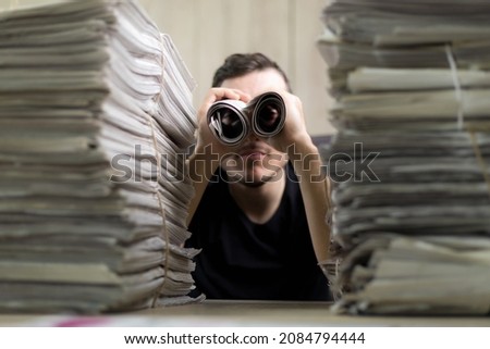 Man holding two twisted roll newspaper. Metaphor or allegory with binoculars. Selective focus on newspapers. Truth search concept Royalty-Free Stock Photo #2084794444