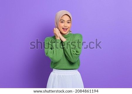 Beautiful smiling Asian woman in green sweater rub hands and looking confident isolated over purple background Royalty-Free Stock Photo #2084861194