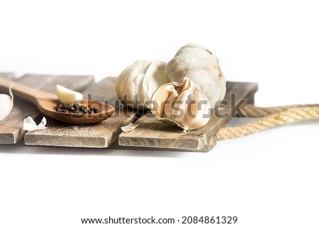 fresh organic garlic isolated over white background, full heads, cloves and peels, wooden spoon with black pepper, cooking ingredients.