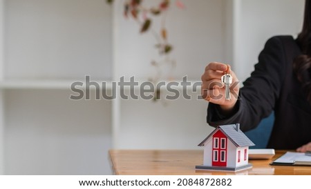 The real estate broker is handing over the house keys to the customer after signing the contract with the dealer in office. Concept of delivering homes to customers after signing the purchase contract