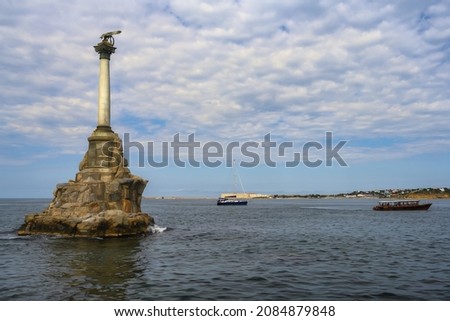 Monument to sunken ships near the Black Sea coast in Sevastopol (Russia) on a summer day. Cove, beautiful relief sky with many clouds. Houses and floating pleasure boats are visible in the distance Royalty-Free Stock Photo #2084879848