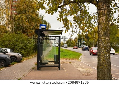 Bus stop with bench in city. Empty bus stop. Cars. Transport concept.  bus stop on city street. In the background  road. Mock up. Poster on street next to roadway. Sunny day. Royalty-Free Stock Photo #2084891236